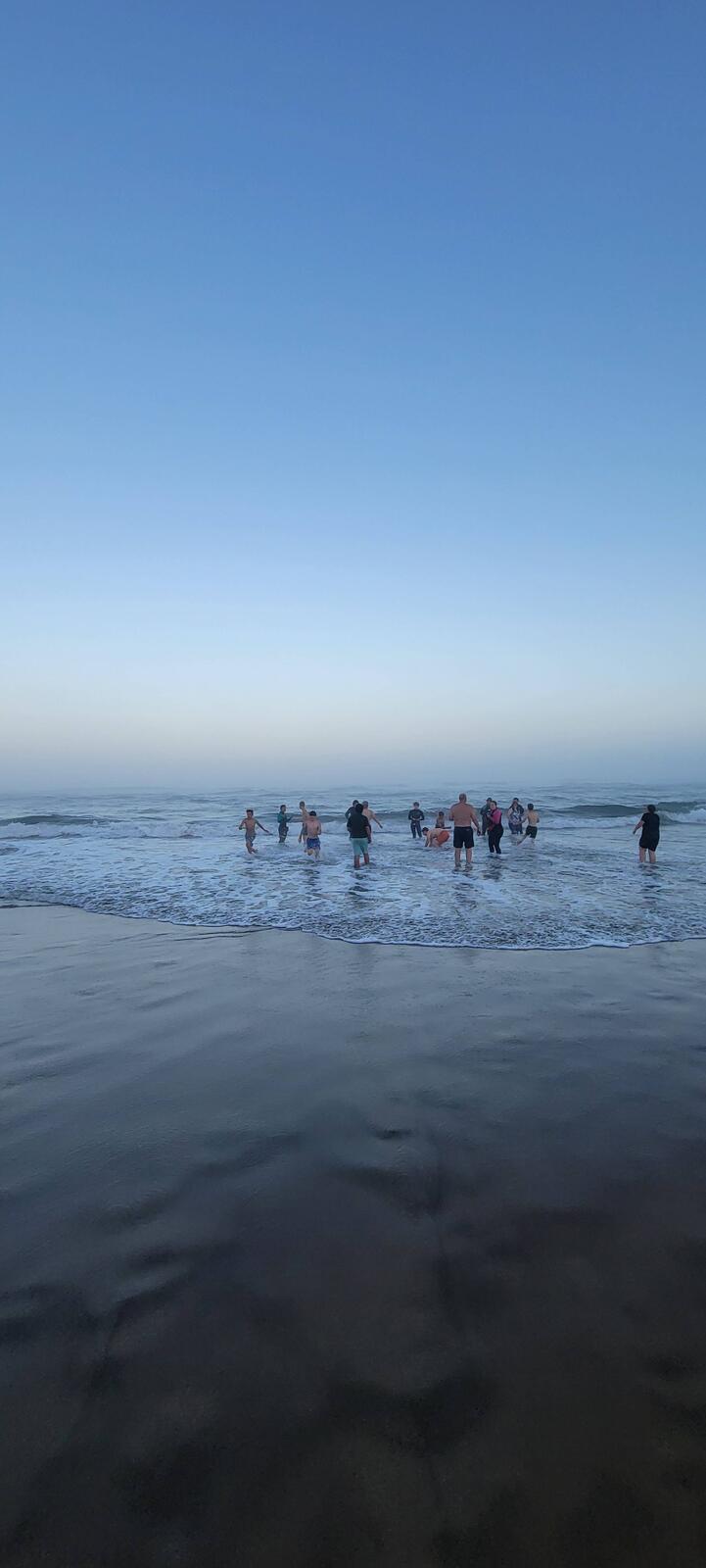 Scouts wading into the ocean at dusk near Camp Meriwether